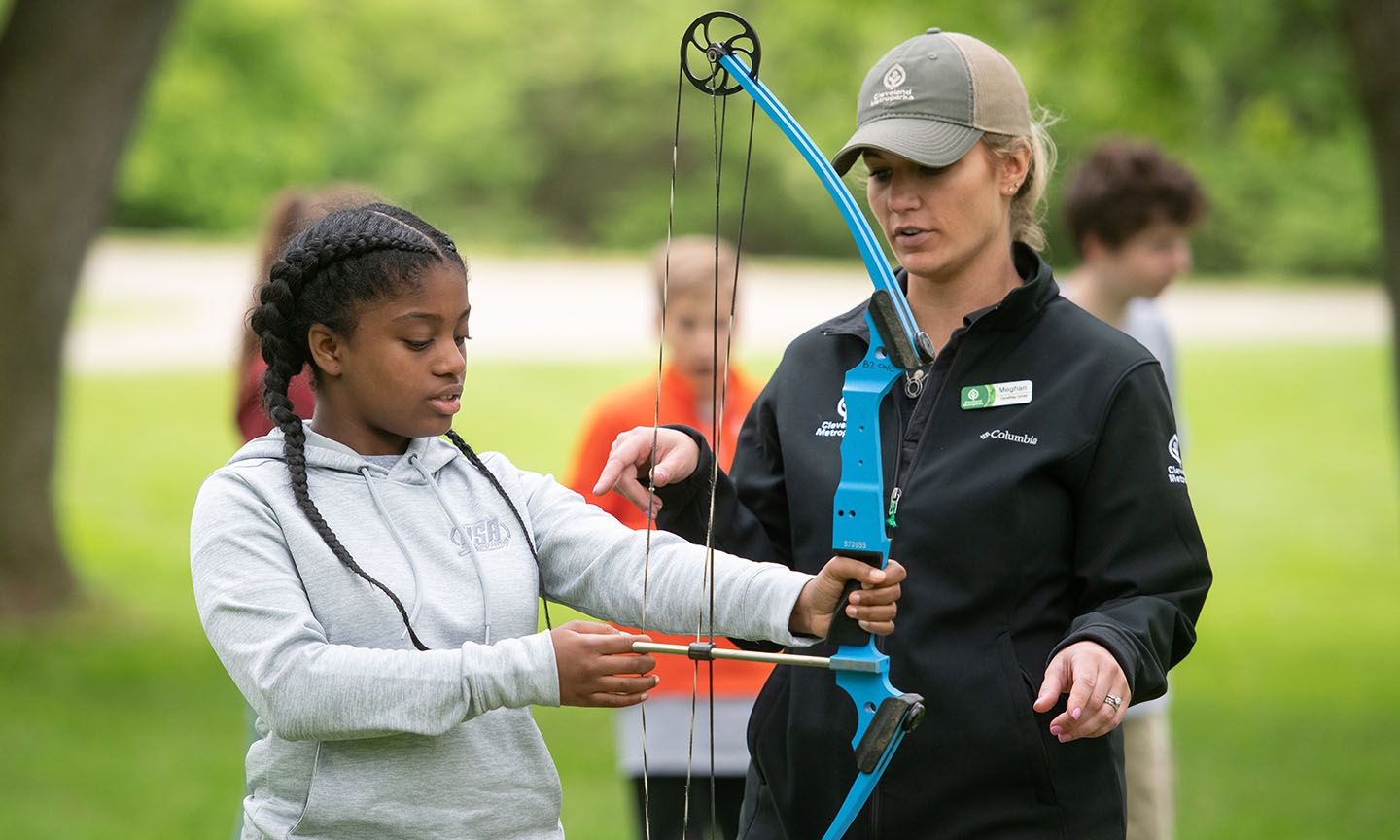 Child learning archery from instructor