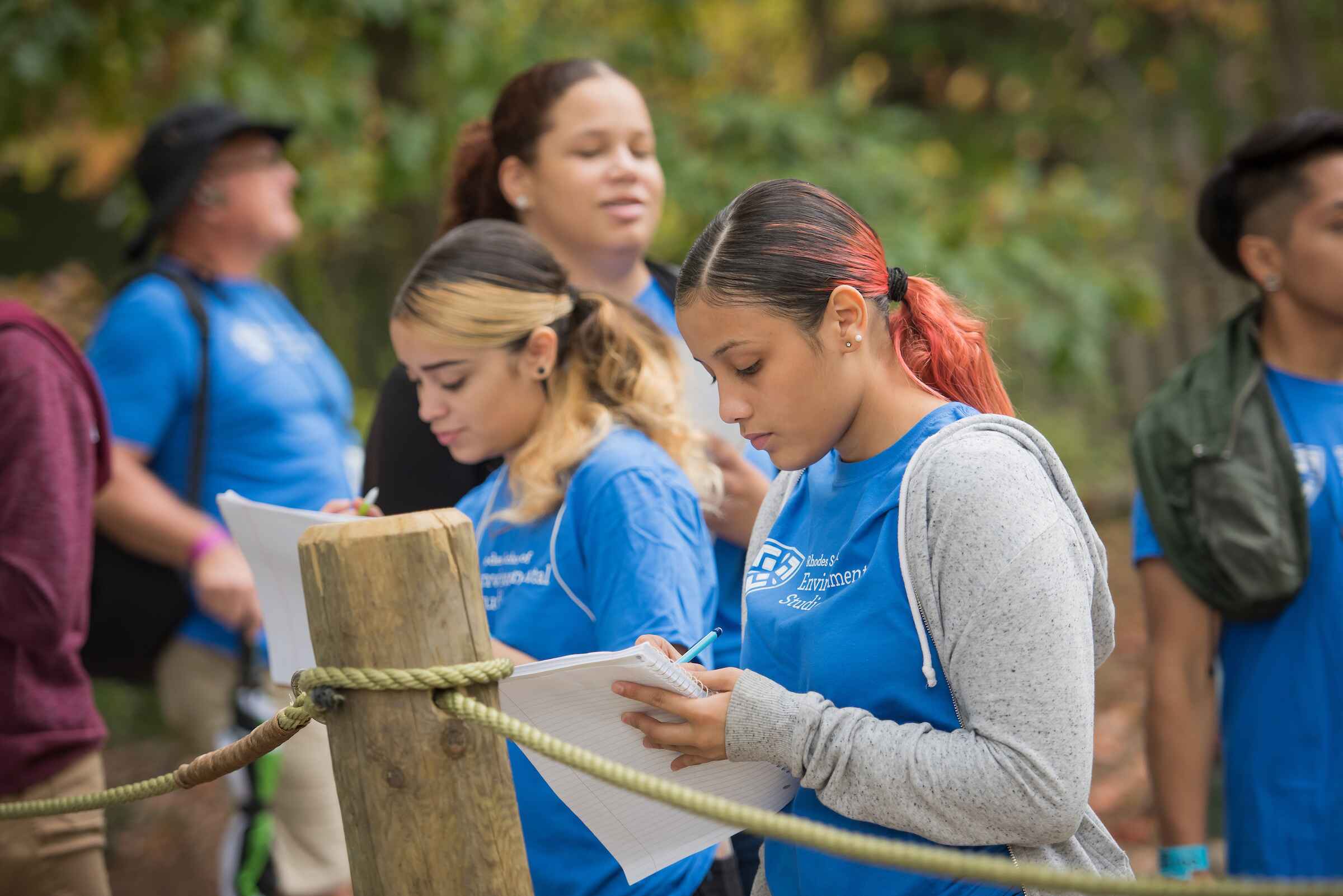 two women in blue shirts filling out paperwork outside 