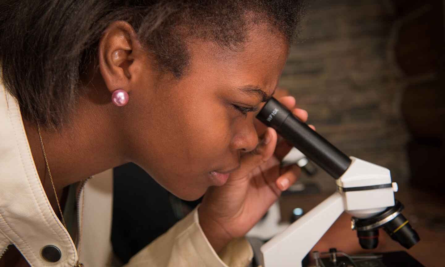 woman looking through microscope