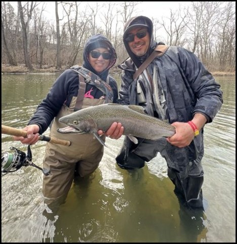 Two men in a river holding a fish