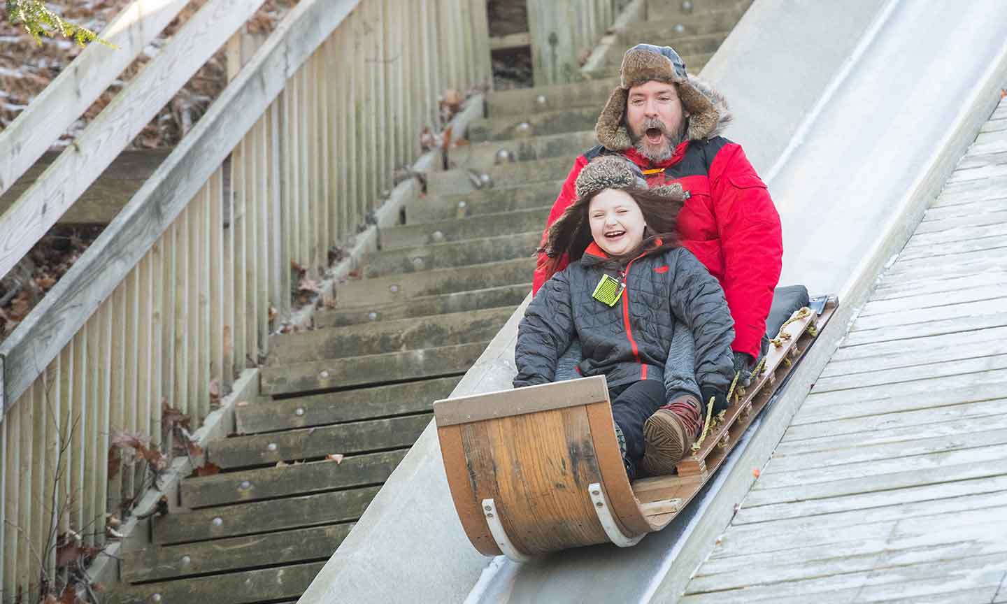 People smiling while riding a toboggan in the snow