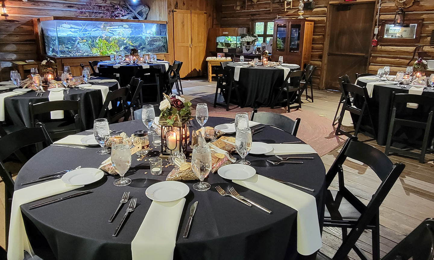 An event room with tables with black cloths and table scapes