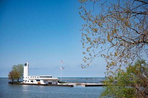 A boat is securely docked at a lighthouse, surrounded by calm waters under a clear sky.