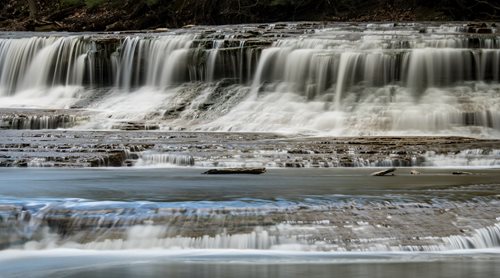 there is a waterfall that is flowing over a rock ledge, an impressionist painting by Mike Bierek, flickr contest winner, art photography, water cascading, cascading waterfalls, a river flowing with waterfall