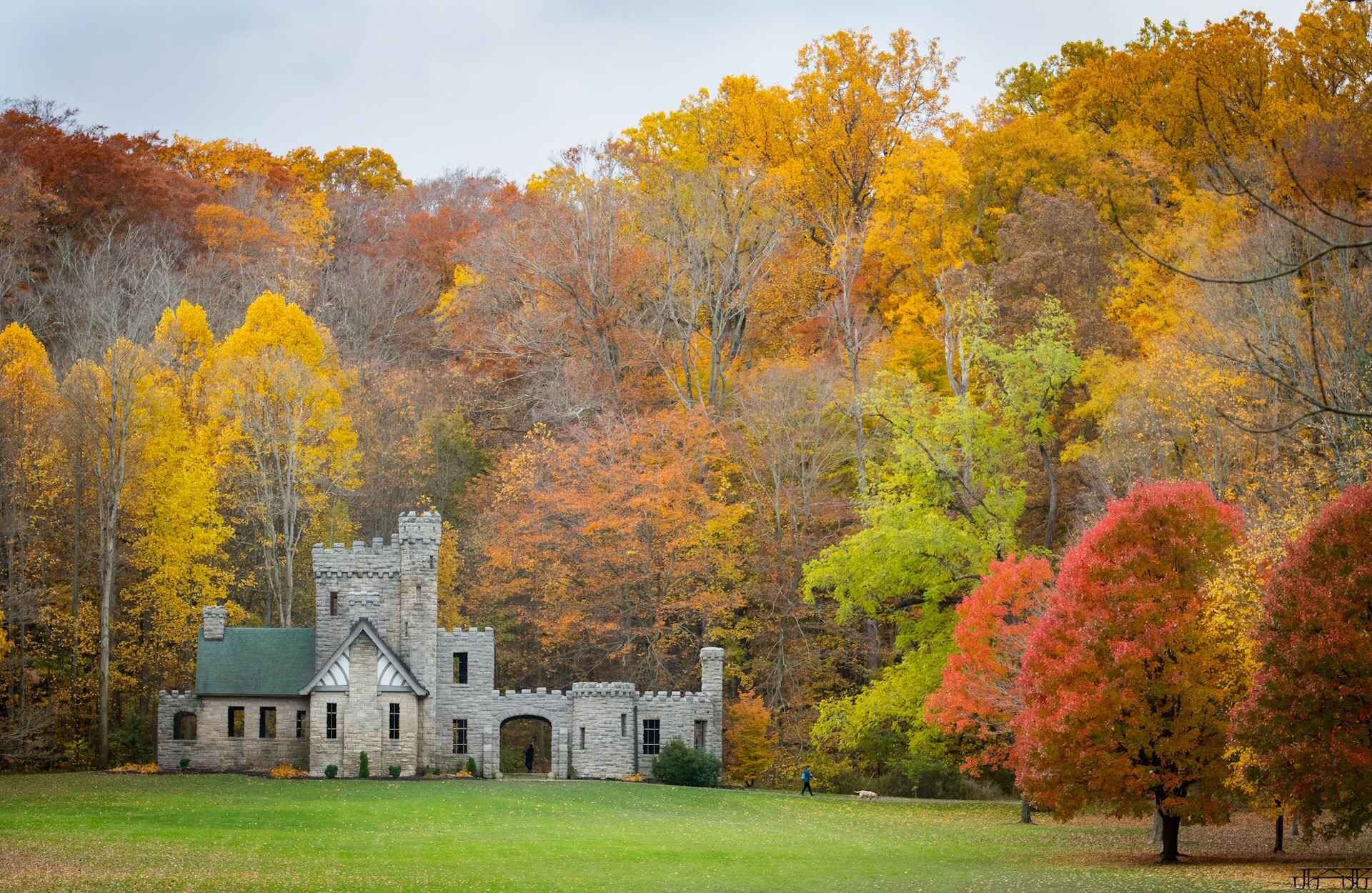 A majestic castle stands in a vibrant field, encircled by colorful autumn foliage, showcasing nature's seasonal beauty.