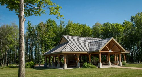 a view of a pavilion with a covered patio in the middle of a field, a digital rendering inspired by Henry Carr, instagram contest winner, arts and crafts movement, covered outdoor stage, galvalume metal roofing, gazebos