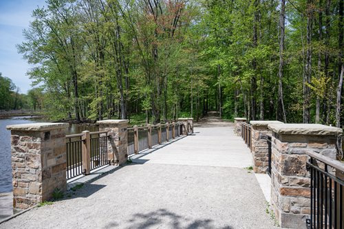 there is a bridge that has a stone walkway over it, a digital rendering inspired by Henry Carr, featured on shutterstock, arts and crafts movement, old stone bridge over the creek, walkway, stone bridge over brook