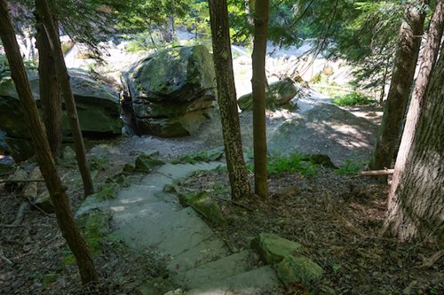 A tranquil path winding through a forest, surrounded by trees and rocky terrain, perfect for a peaceful walk.